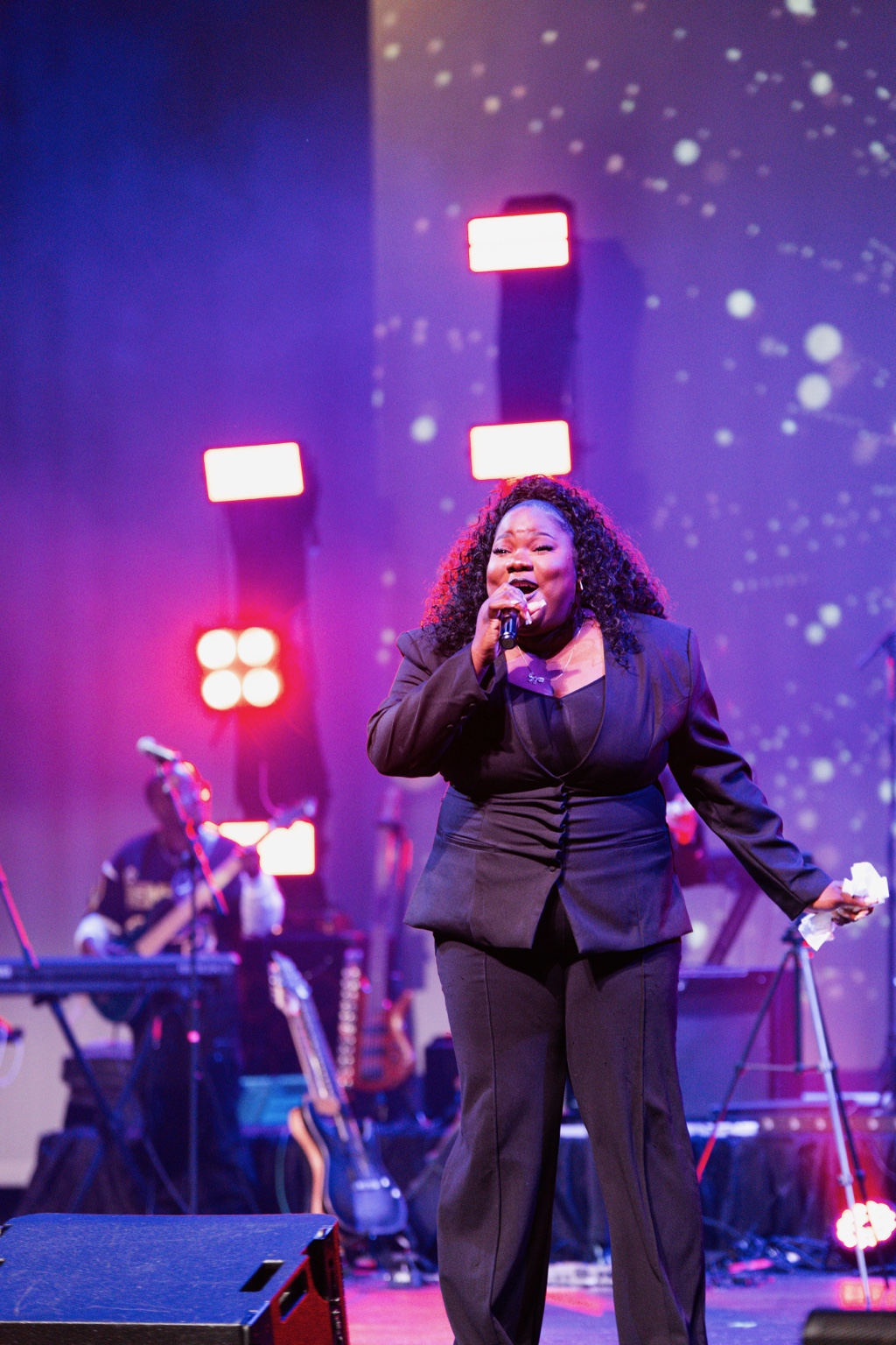 Gloria Bila singing onstage under purple and red lights